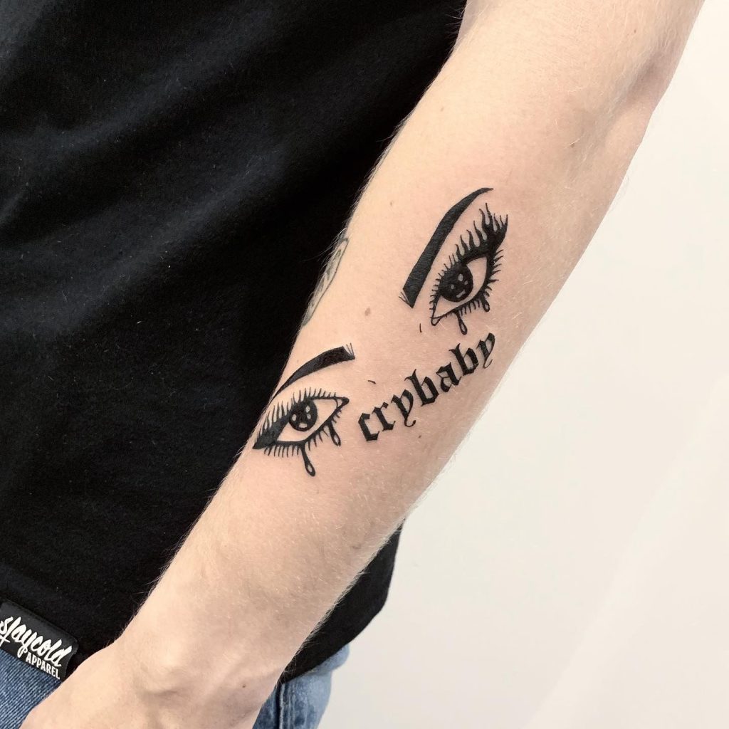Cry baby tattoo with eyes on forearm