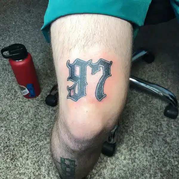 97 written above knee tattoo