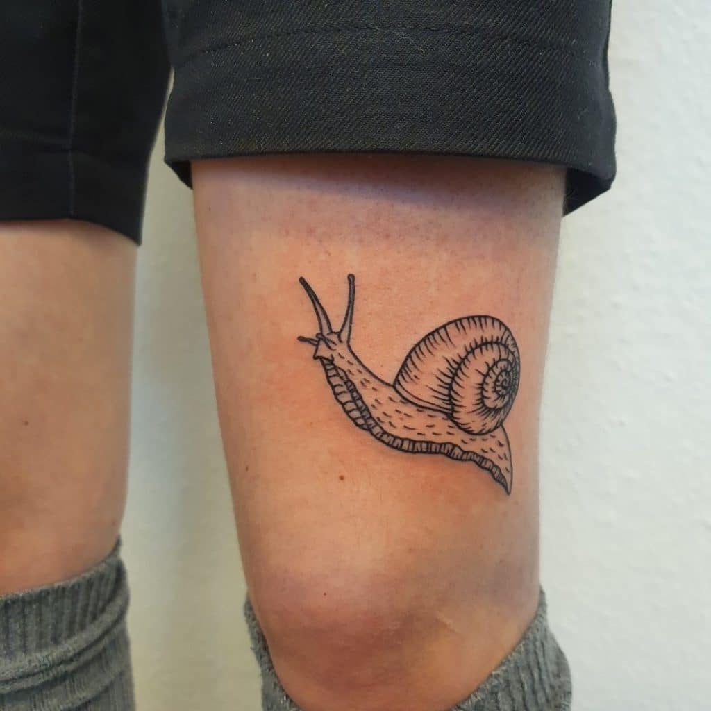 Snail above knee tattoo
