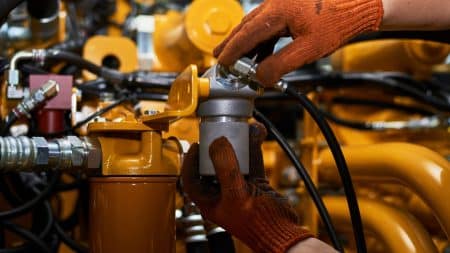 Low key photo of hydraulic pipes maintenance on heavy industry machine.